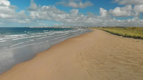 Aerial Shot of waves breaking along a beautiful beach with cloudy blue sky Stock Footage 99077447