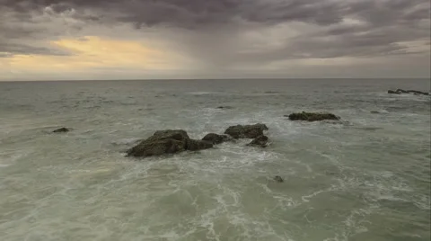 Aerial shot of waves hitting rocks with a cloudy sky Vidéo 67596466