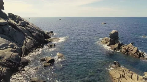 Aerial shot of waves hitting rocks on a sunny summer day Stock-Footage 134813676