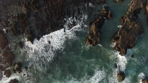 Aerial shot of the waves hitting the rocks in bali Vidéo 303629992