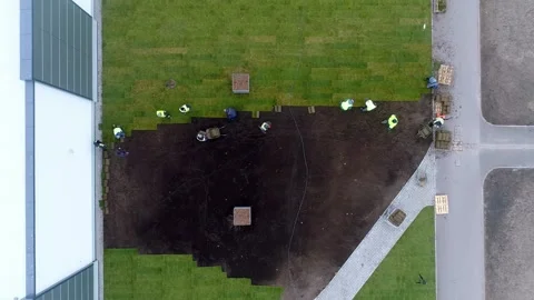 Aerial Shot of Workers Skillfully Laying Sod Beside Modern Architecture Video stock 315264667