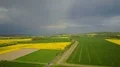 Aerial shot yellow blooming rape fields dark thunderstorm clouds and rainbow 4k or 4k+ Resolution