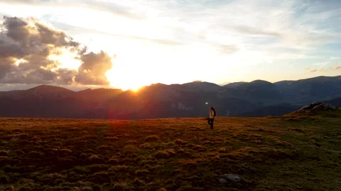 Aerial side drone view of young woman hiker walking on a hill at sunset Stock Footage 276678058
