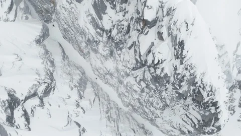 Aerial of side of structured mountain covered in thick layers of heavy snow Stock Footage 121596235