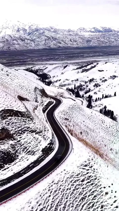 Aerial side-tracking shot of a black car driving on a winding mountain road Video stock 328566185