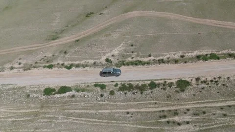 Aerial side tracking shot of an SUV driving through the steppe, Kyrgyzstan Видео 347240980