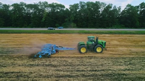 Aerial side view of an agricultural work in the field: tractor plowing the soil Stock-Footage 242345820
