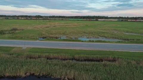 Aerial side view of an intercity road with traffic and railway between green Video stock 209141485