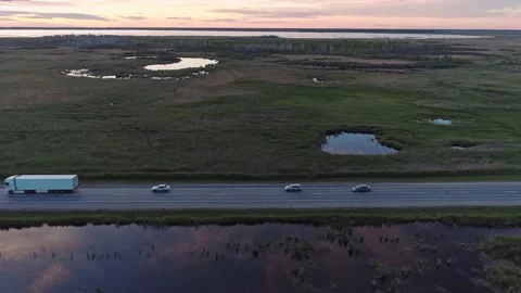 Aerial side view of an intercity road with traffic between green fields in Video stock 217952373