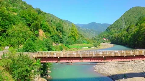 Aerial side view of a man crossing a bridge in Georgia over the Chorokhi River, Video stock 161222502