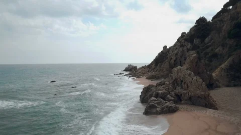 Aerial side view of the ocean waves hitting the sandy beach below the cliff Stock Footage 92696837