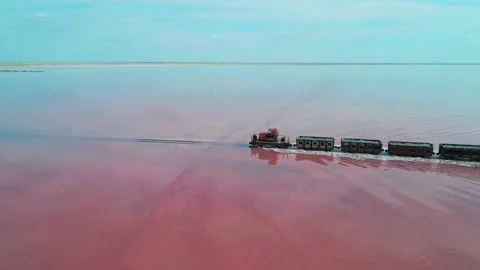 Aerial side view of an old train rides on the railway laid in the water through Stock Footage 231602582