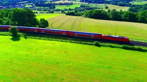 Aerial side view of regional passenger train crossing green farmland in rural Stock Footage 337141647