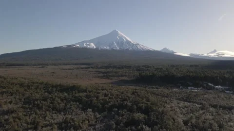 Aerial side view of the snow-covered Osorno Volcano with the forest visible Stock Footage 249893723