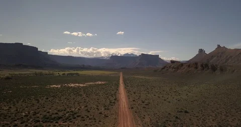 Aerial - sinking down toward red dirt road in beautiful mountain valley Stock Footage 107115370