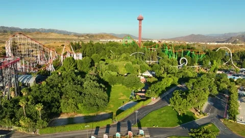 Aerial Six Flags Magic Mountain roller coaster and water rides, green trees  Stock Footage 244597510