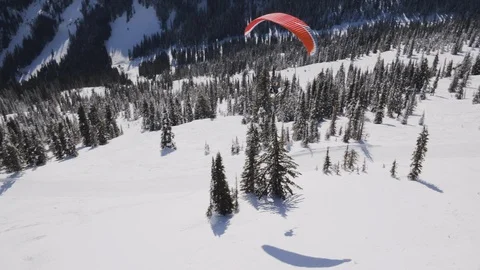 Aerial of skier using parachuting over snowy ski resort during sunny day, Canada Video stock 121586925
