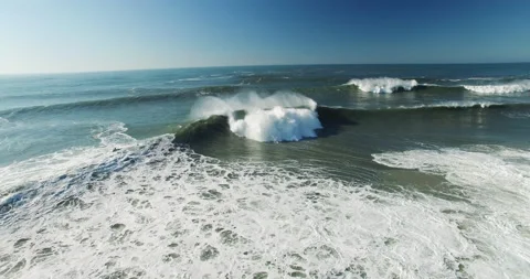 Aerial slow motion of breaking ocean waves splashing around during sunny day Stock Footage 155665126