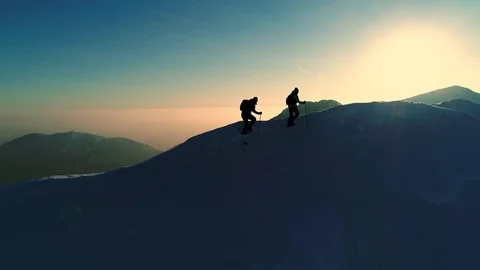Aerial slow motion - Flying over two male mountaineers hiking on snowy mountain  Stock Footage 82512971