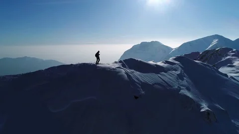 Aerial, slow motion - Man hiking on top of snowy mountain at beautiful sunset Stock Footage