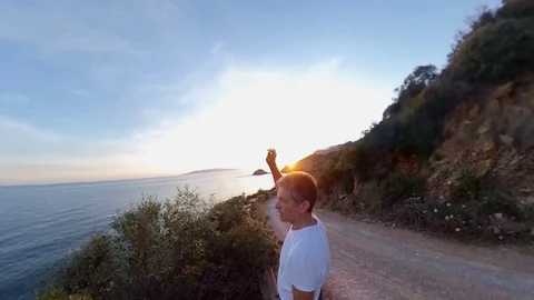 Aerial Slow Motion, a man standing near a scenic path on the cliff  at sunset Stock Footage 107913482