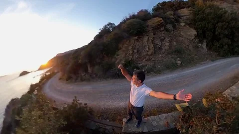 Aerial Slow Motion, a man standing near a scenic path on the cliff  at sunset Stock Footage 107920989