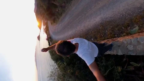 Aerial Slow Motion, a man standing near a scenic path on the cliff  at sunset Stock Footage 107921056