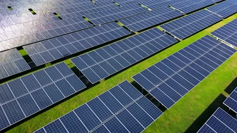 Aerial slow motion orbit view of blue solar power panels at sunset in the green Vidéo 236149345
