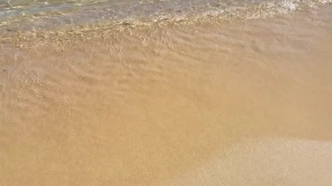 Aerial slow motion tracking shot of waves washing across sandy shore and re.. Stock Footage 329871055