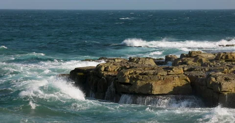 Aerial slow motion view of waves breaking against rocks on a rocky coastline Stock Footage 153845291