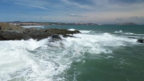 Aerial slow motion view of waves breaking against rocks on a rocky coastline Stock Footage 263948313