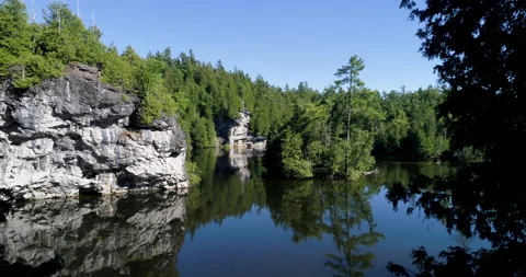 Aerial Slow Through Trees Over Beautiful Wilderness Lake With Lime Stone Cliffs Video stock 188808097
