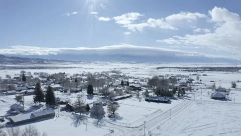 Aerial-Small mountain valley town in new snow toward sun Video stock 148347380