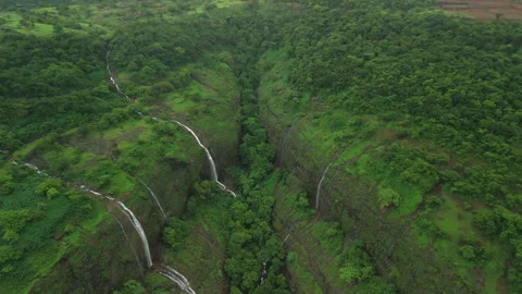 Aerial: Smooth reverse flight down canyon reveals twin cliffs roaring with rain Stock Footage 346254730