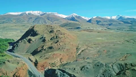 Aerial of snow capped mountain range, green valley and highway along the Stock Footage 209176189