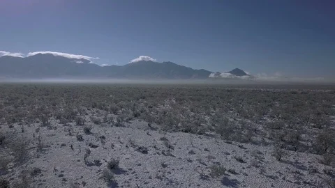 Aerial of a snow covered desert with distant mountains Stock Footage 100565395