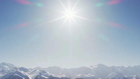 Aerial spinning circular view bright sunburst radiating above snow covered .. Stock-Footage 328408941