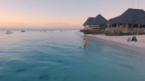 AERIAL: Stand up paddling at orange sunset in the ocean near the coast of Africa Stock Footage 77438545