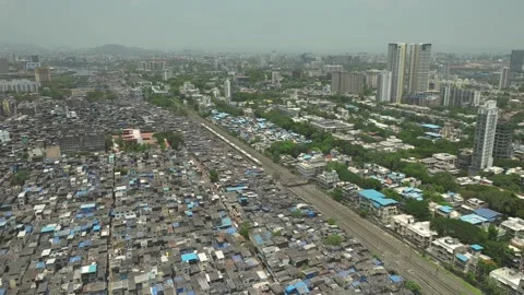 Aerial static shot of train passing next to the Dharavi slum in Mumbai, Stock Footage 243263991