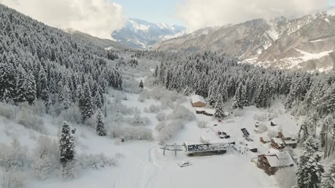 Aerial static snow covered pine forest and wooden hut near ski resort in Me.. Vidéo 324968596