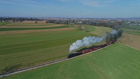 Aerial of a Steam Train With Red Freight Cars Moves Through Vast, Patchwork.. Video stock 282070013