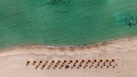Aerial of straw umbrellas at empty beach near the shore, Simos beach Stock Footage 338164838