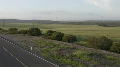 Aerial subcompact car passing by at open green field surrounding highway Stock Footage 184426334