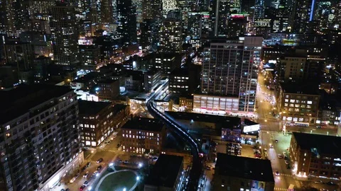 Aerial - Subway Train on Elevated Track Maneuvering Downtown City at Night Stock Footage 121461560