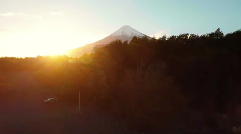 Aerial: Sun behind volcano reveal behind forrest at sunrise Patagonia 2K Stock Footage 64671253