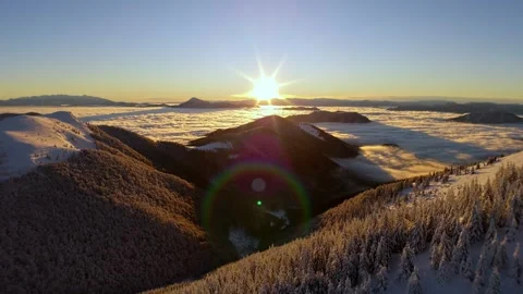 Aerial sunrise pullback over winter mountains above sea of clouds inversion in Video stock 323380979