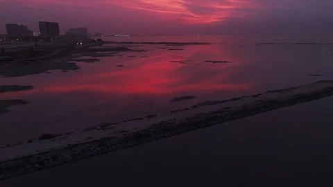 Aerial sunset coastline with dramatic red sky reflecting over calm coastal Stock Footage 329477468