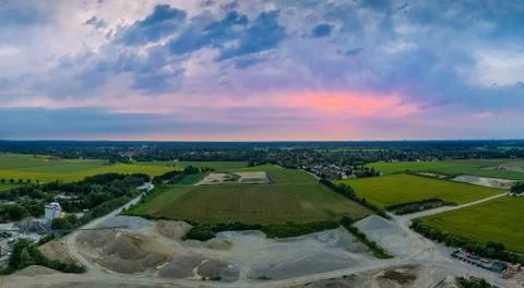 Aerial sunset with a construction area, fields and a city. Stock Photos