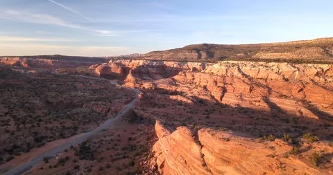 Aerial sunset on desert road with deep canyons and red rocks Stock Footage 99558011