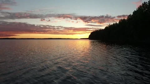 Aerial Sunset over Forest Lake Shore in Finland – Calm Water and Colorful Sky Stock Footage 148998901